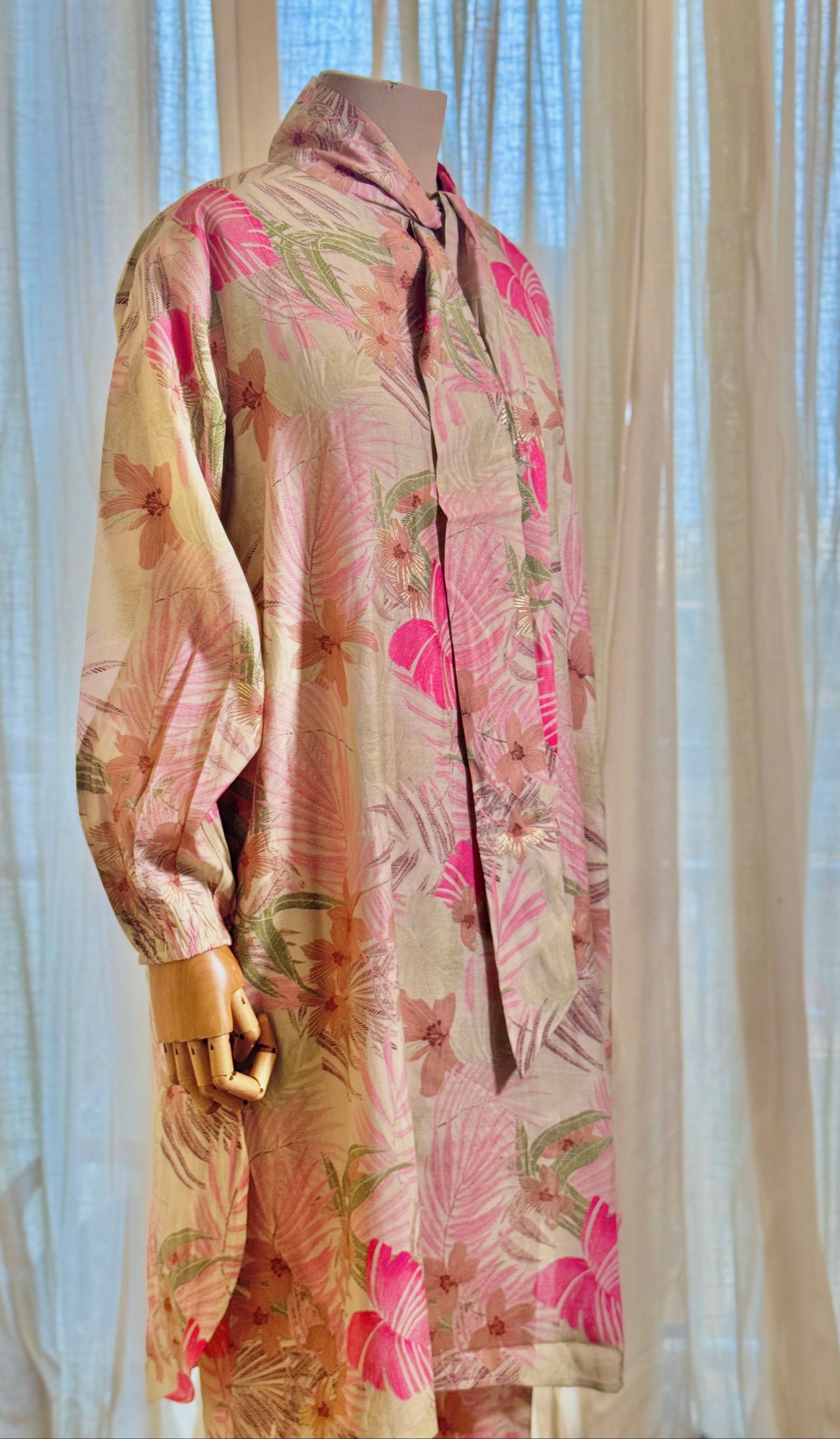Floral patterned coat on a mannequin against a sheer curtain background
