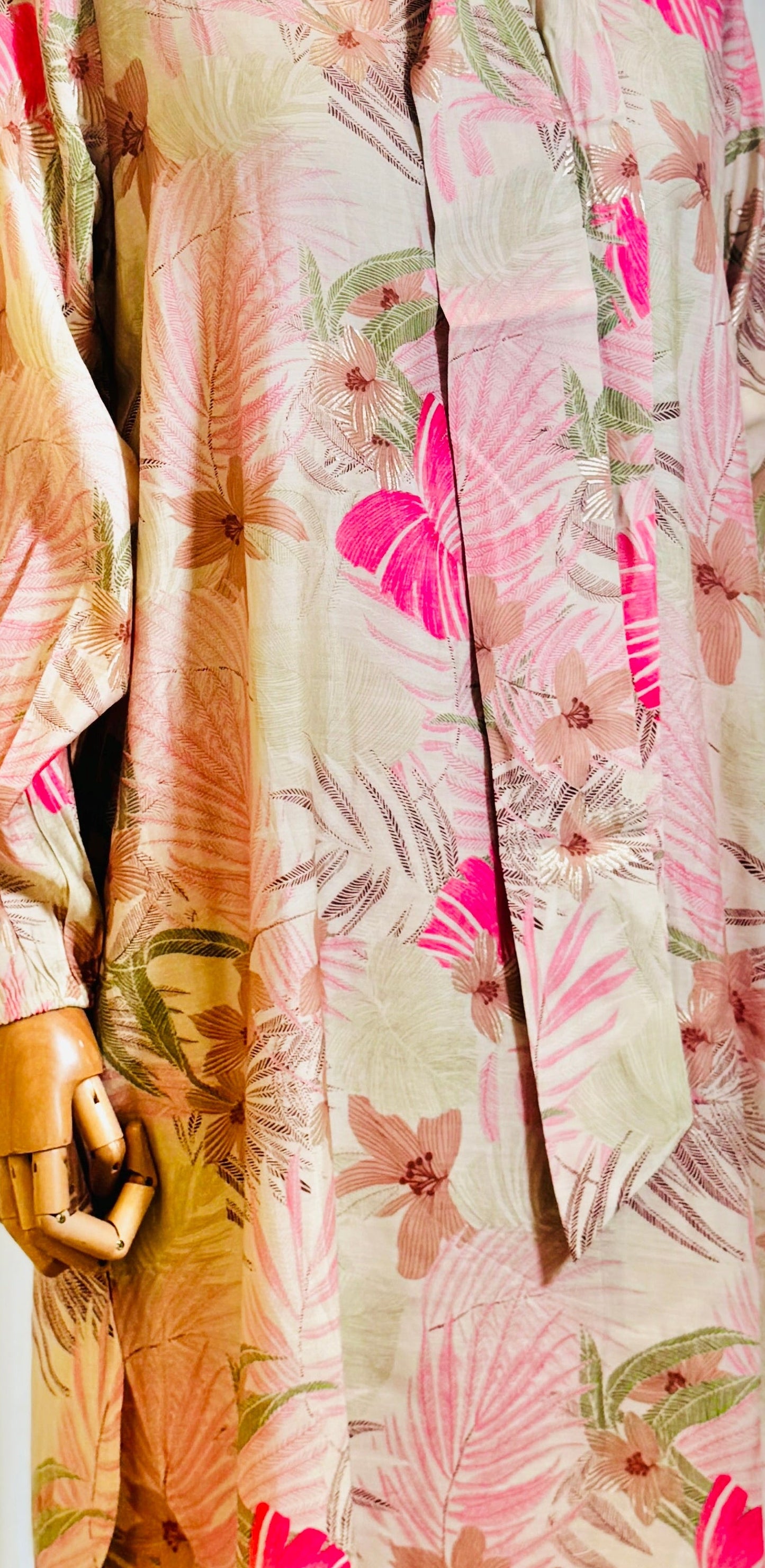 Floral patterned dress on a mannequin against a white curtain background