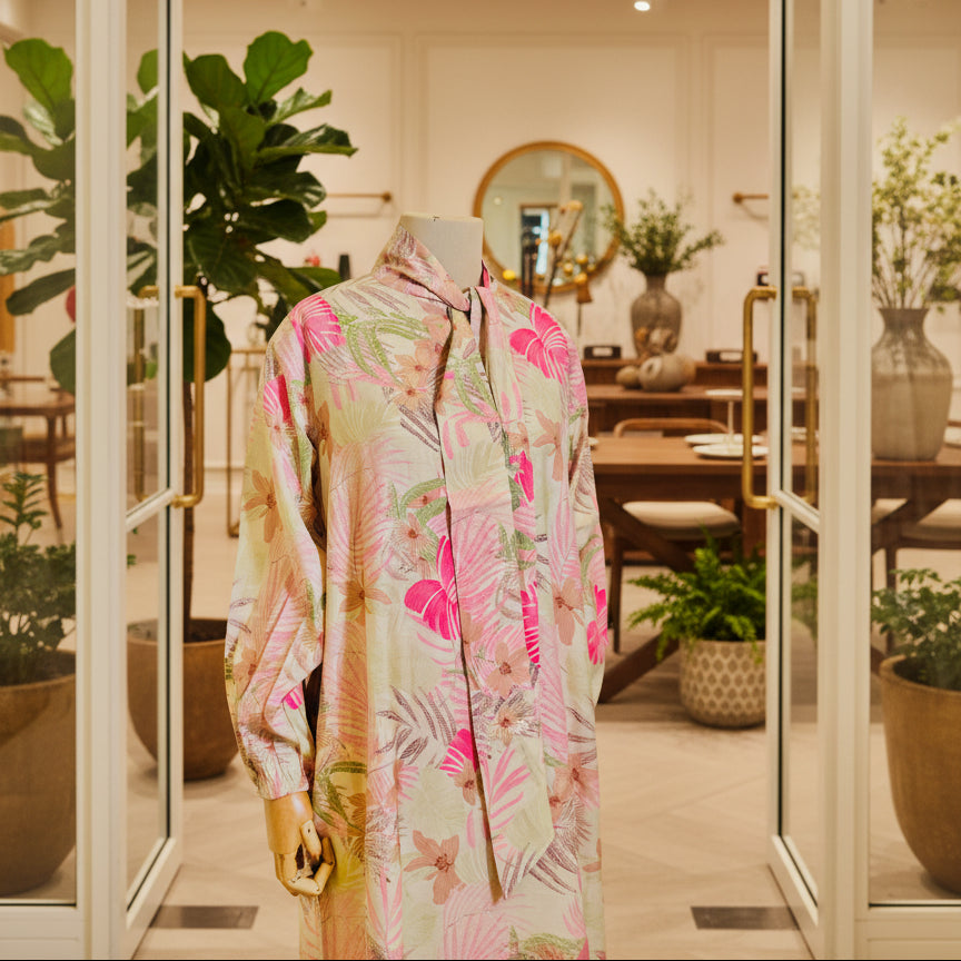 Floral patterned shirt on a mannequin in a store setting with plants and furniture.