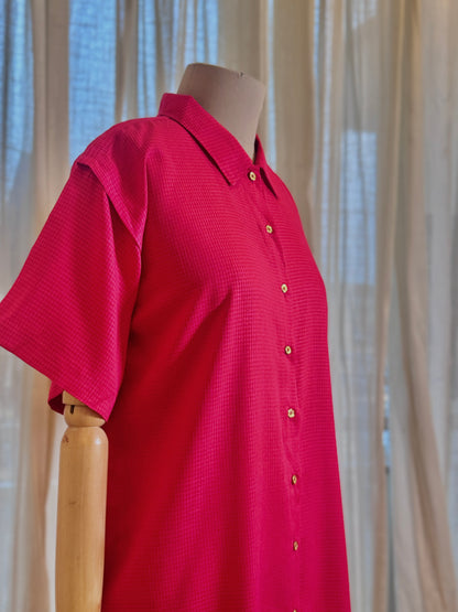 Red shirt on a mannequin against a neutral curtain background