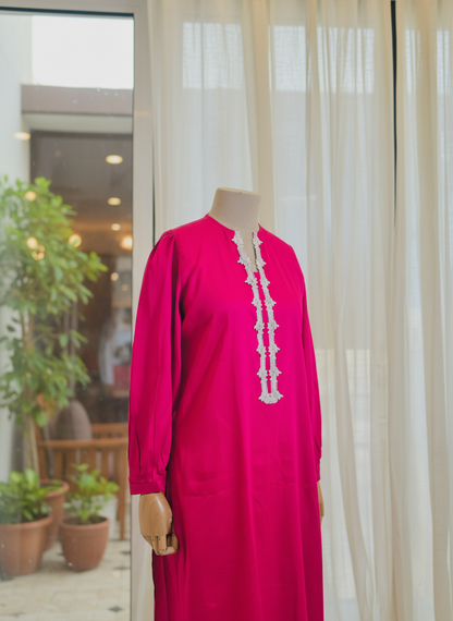 Pink dress with white lace details on a mannequin against a neutral background