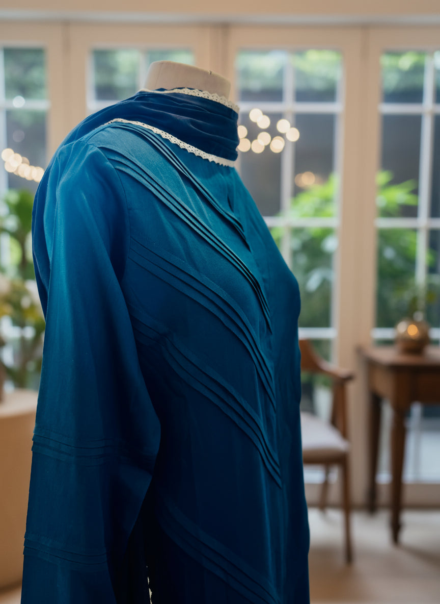 Teal dress on a mannequin against a blurred indoor background