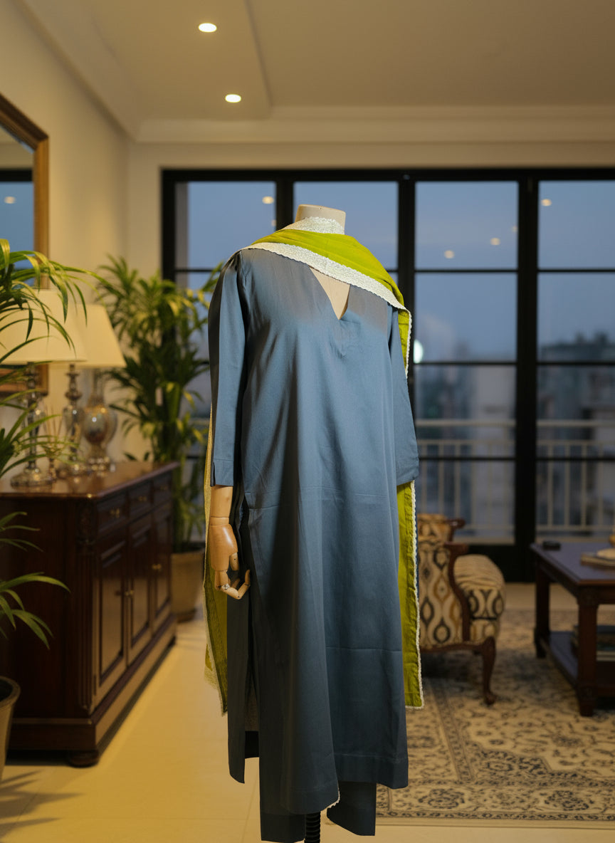 Mannequin wearing a blue dress with green accents against a window backdrop