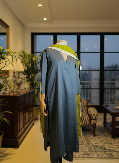 Mannequin wearing a blue dress with green accents against a window backdrop