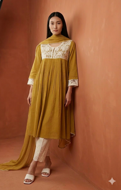 Woman wearing a mustard yellow dress with white lace details against a brown background