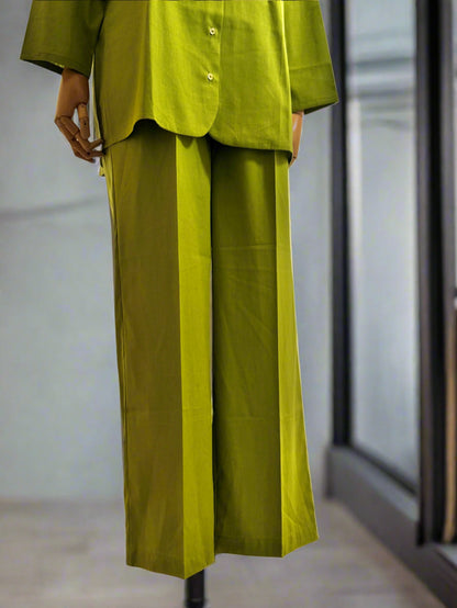 Person wearing a green outfit standing in front of sheer curtains